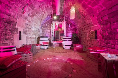 Comptoir lumineux dans une pièce voûtée en pierre, décoré de plantes, lampes et guirlandes lumineuses.