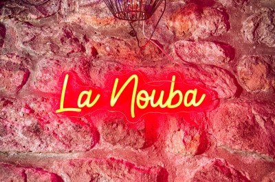 Comptoir lumineux dans une pièce voûtée en pierre, décoré de plantes, lampes et guirlandes lumineuses.