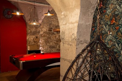 Comptoir lumineux dans une pièce voûtée en pierre, décoré de plantes, lampes et guirlandes lumineuses.