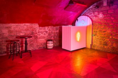 Comptoir lumineux dans une pièce voûtée en pierre, décoré de plantes, lampes et guirlandes lumineuses.