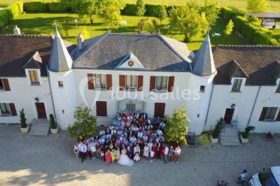 Miniature Location salle Gironville (Seine-et-Marne) - Domaine Saint Pierre #3 Champ de coquelicots rouges au premier plan avec un bâtiment en pierre et des toits en arrière-plan sous un ciel nuageux.