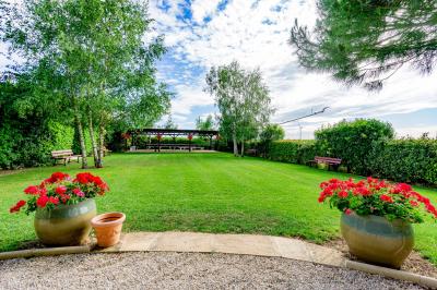 Miniature Location salle Gironville (Seine-et-Marne) - Domaine Saint Pierre #20 Champ de coquelicots rouges au premier plan avec un bâtiment en pierre et des toits en arrière-plan sous un ciel nuageux.