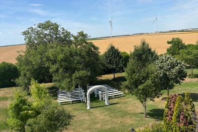 Miniature Location salle Gironville (Seine-et-Marne) - Domaine Saint Pierre #23 Champ de coquelicots rouges au premier plan avec un bâtiment en pierre et des toits en arrière-plan sous un ciel nuageux.