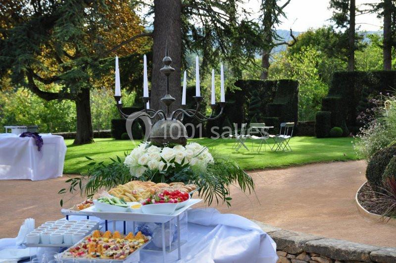 Buffet dressé en extérieur avec chandeliers, fleurs blanches et plats variés, dans un jardin arboré.