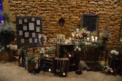 Cour éclairée au crépuscule avec des bâtiments en pierre, des torches allumées et des personnes en arrière-plan.