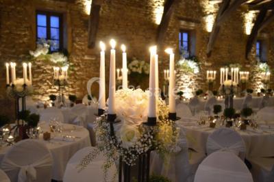 Cour éclairée au crépuscule avec des bâtiments en pierre, des torches allumées et des personnes en arrière-plan.