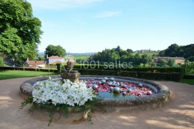 Cour éclairée au crépuscule avec des bâtiments en pierre, des torches allumées et des personnes en arrière-plan.