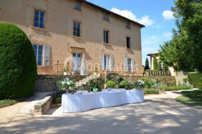 Cour éclairée au crépuscule avec des bâtiments en pierre, des torches allumées et des personnes en arrière-plan.