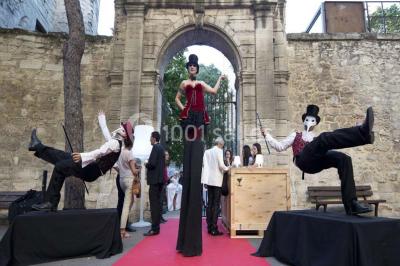 Façade vitrée d'un bâtiment moderne avec éclairages rouges, intégrée à des murs en pierre ancienne.