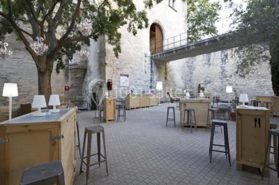 Façade vitrée d'un bâtiment moderne avec éclairages rouges, intégrée à des murs en pierre ancienne.