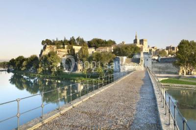 Façade vitrée d'un bâtiment moderne avec éclairages rouges, intégrée à des murs en pierre ancienne.