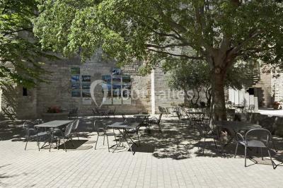 Façade vitrée d'un bâtiment moderne avec éclairages rouges, intégrée à des murs en pierre ancienne.