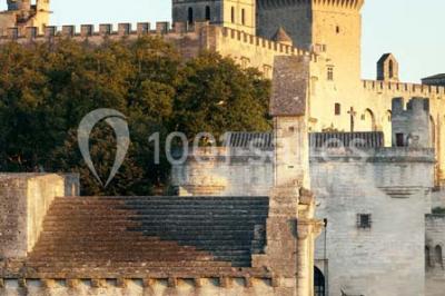 Façade vitrée d'un bâtiment moderne avec éclairages rouges, intégrée à des murs en pierre ancienne.