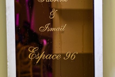 Verres de cocktails colorés garnis de fruits et de feuilles, disposés sur une table lors d'un événement en extérieur.