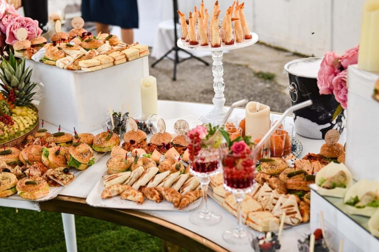 Buffet de réception avec une variété de bouchées salées, desserts, fruits et décorations florales.