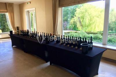 Salle de réception avec tables rondes dressées, nappes blanches, assiettes dorées et décoration florale centrale.