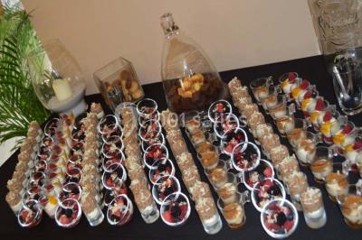 Salle de réception avec tables rondes dressées, nappes blanches, assiettes dorées et décoration florale centrale.