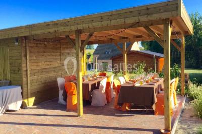Salle de réception avec tables rondes dressées, nappes blanches, assiettes dorées et décoration florale centrale.