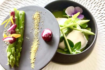 Salle de réception avec tables rondes dressées, nappes blanches, assiettes dorées et décoration florale centrale.