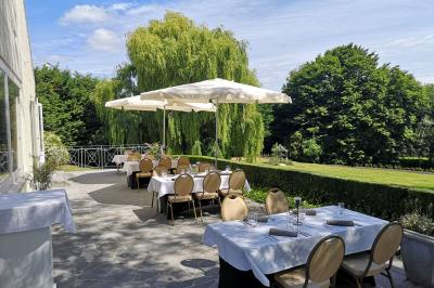 Salle de réception avec tables rondes dressées, nappes blanches, assiettes dorées et décoration florale centrale.