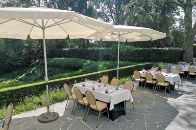 Salle de réception avec tables rondes dressées, nappes blanches, assiettes dorées et décoration florale centrale.