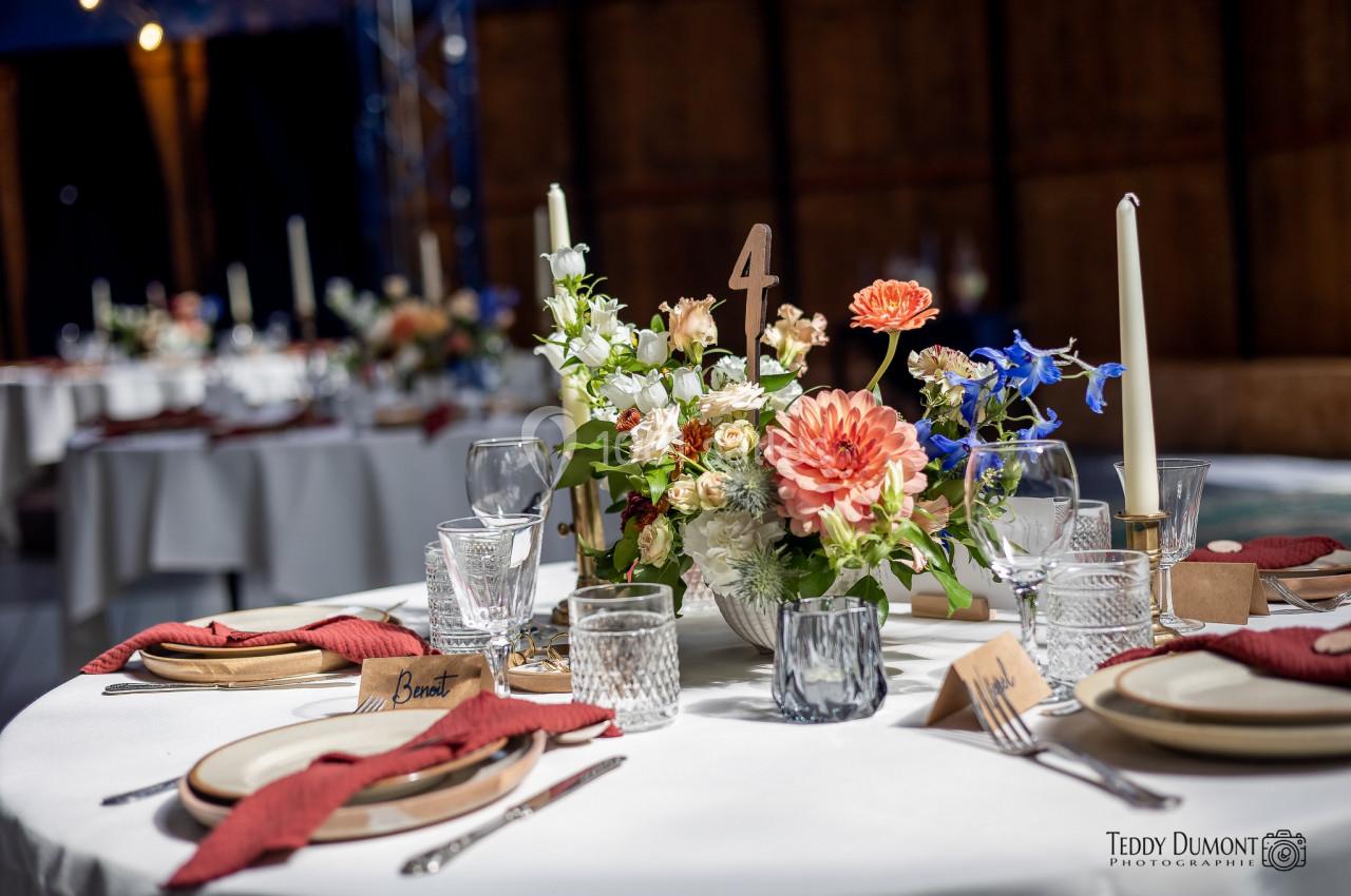 Table dressée avec élégance, décorée de fleurs colorées, bougies et vaisselle raffinée dans un cadre chaleureux.