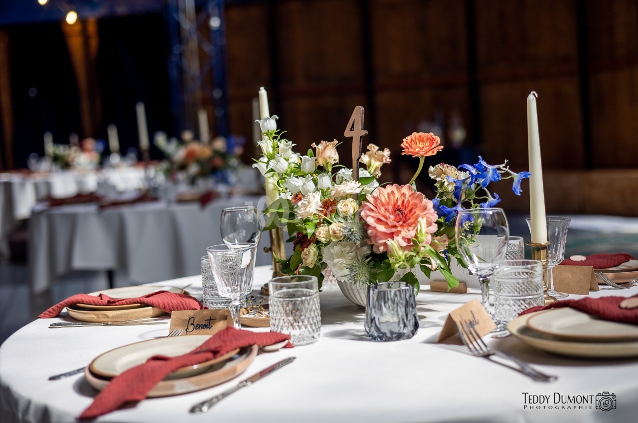 Table dressée avec élégance, décorée de fleurs colorées, bougies et vaisselle raffinée dans un cadre chaleureux.