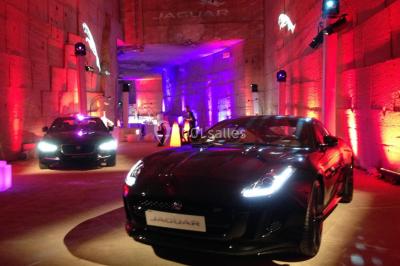 Salle décorée pour un événement avec des tables hautes éclairées et des lumières colorées en arrière-plan.