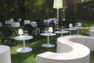 Salle décorée pour un événement avec des tables hautes éclairées et des lumières colorées en arrière-plan.