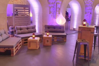 Salle décorée pour un événement avec des tables hautes éclairées et des lumières colorées en arrière-plan.