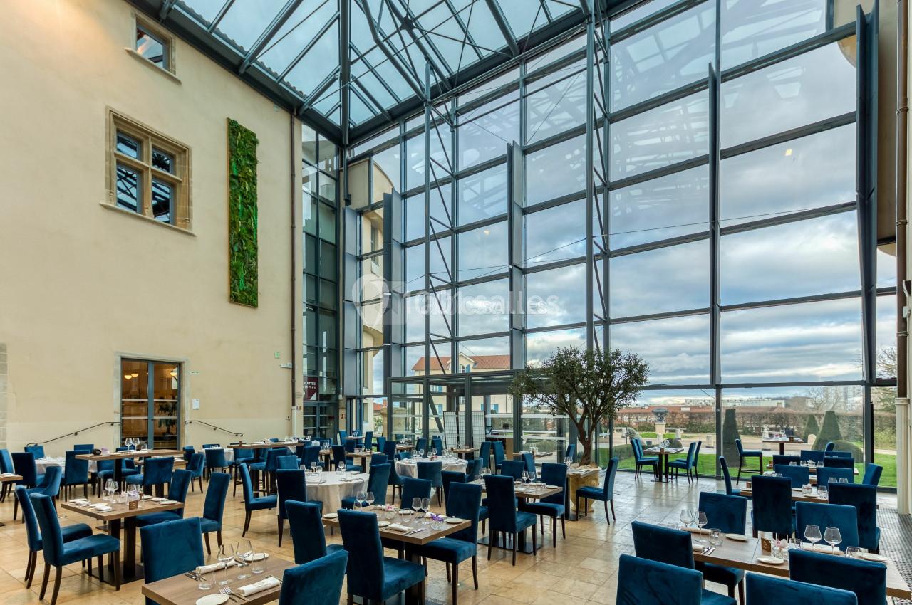 Location salle Saint-Priest (Rhône) - Château de Saint Priest #8 Salle de restaurant lumineuse avec de grandes baies vitrées, des tables dressées et des chaises bleues.