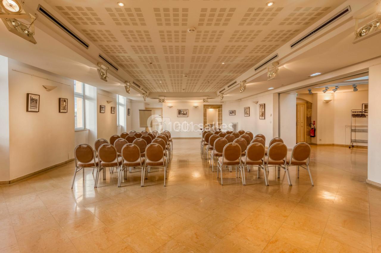 Location salle Saint-Priest (Rhône) - Château de Saint Priest #2 Salle lumineuse avec des rangées de chaises disposées face à un mur blanc, éclairée par des spots au plafond.