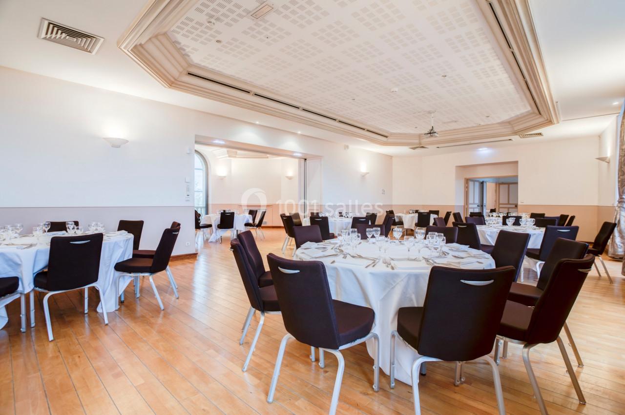 Location salle Saint-Priest (Rhône) - Château de Saint Priest #10 Salle de réception lumineuse avec tables rondes dressées, chaises noires et parquet en bois clair.