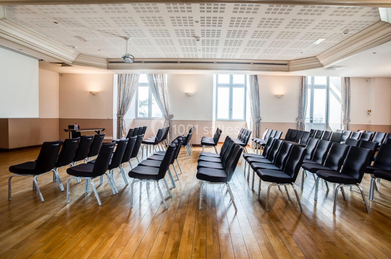 Location salle Saint-Priest (Rhône) - Château de Saint Priest #3 Salle lumineuse avec parquet, rangées de chaises noires alignées face à un écran de projection.