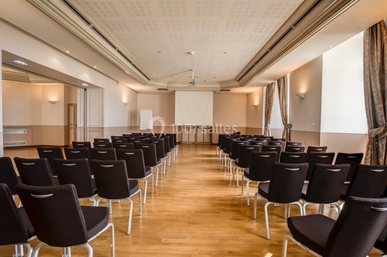 Location salle Saint-Priest (Rhône) - Château de Saint Priest #6 Salle de conférence vide avec des rangées de chaises noires, un écran de projection et un tableau blanc à l'arrière.