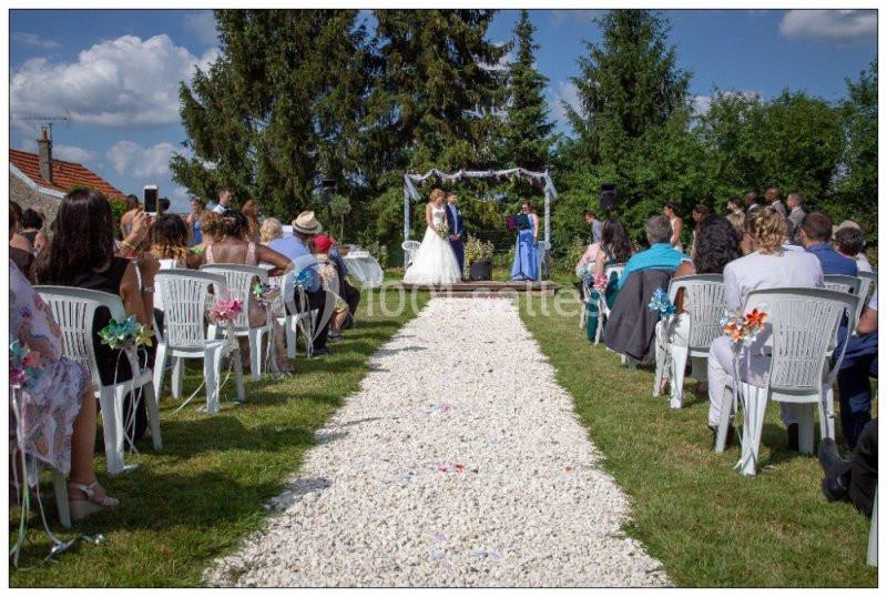 Cérémonie de mariage en plein air avec des invités assis de part et d'autre d'une allée décorée de gravier blanc.