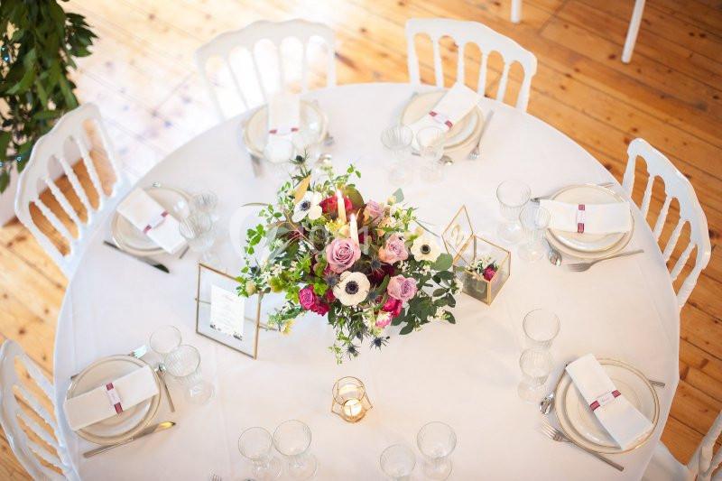 Location salle Fontains (Seine-et-Marne) - Château de Bourguignon #13 Table ronde décorée avec une nappe blanche, un centre de table floral coloré et des couverts élégamment disposés.