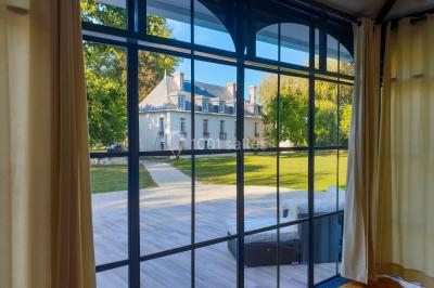 Miniature Location salle Fontains (Seine-et-Marne) - Château de Bourguignon #6 Vue nocturne d'une verrière illuminée par des lumières violettes, entourée d'arbres et d'un jardin.