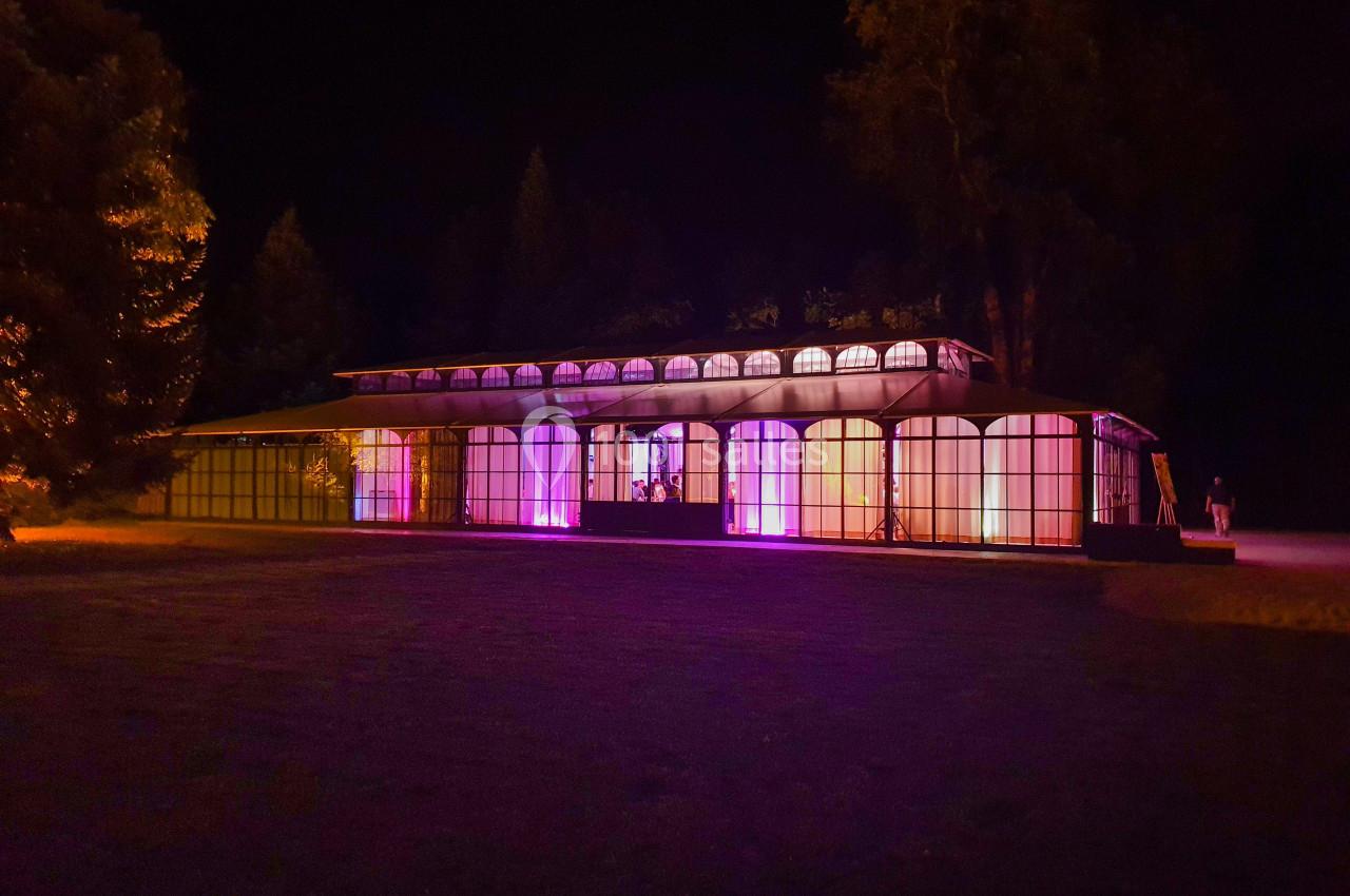 Location salle Fontains (Seine-et-Marne) - Château de Bourguignon #17 Bâtiment vitré illuminé par des lumières colorées dans un environnement extérieur nocturne.