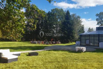 Miniature Location salle Fontains (Seine-et-Marne) - Château de Bourguignon #8 Vue nocturne d'une verrière illuminée par des lumières violettes, entourée d'arbres et d'un jardin.