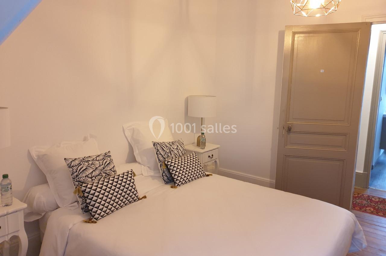 Location salle Fontains (Seine-et-Marne) - Château de Bourguignon #27 Chambre lumineuse avec un lit double, des coussins décoratifs, deux lampes de chevet et une porte beige.