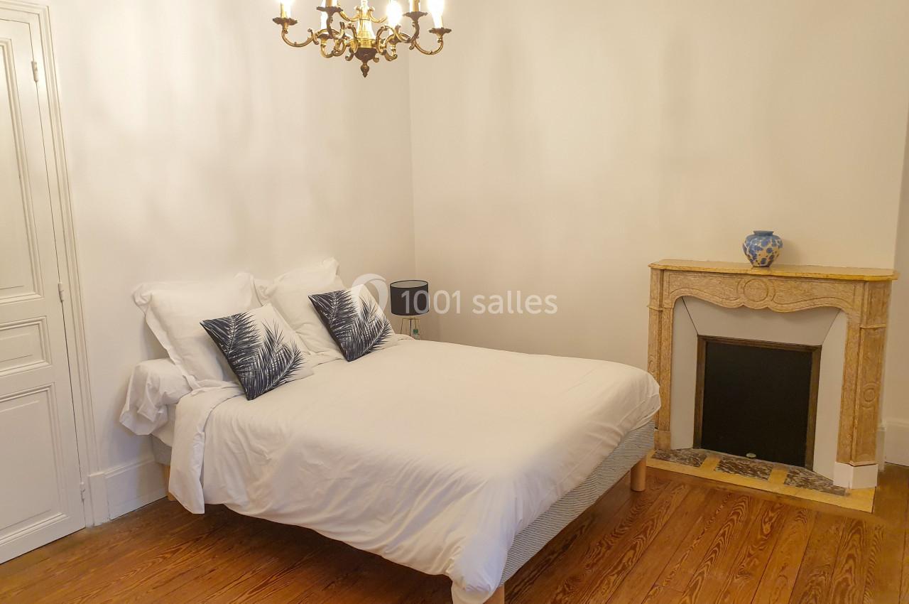 Location salle Fontains (Seine-et-Marne) - Château de Bourguignon #28 Chambre avec un lit double, cheminée décorative, parquet en bois et lustre suspendu.