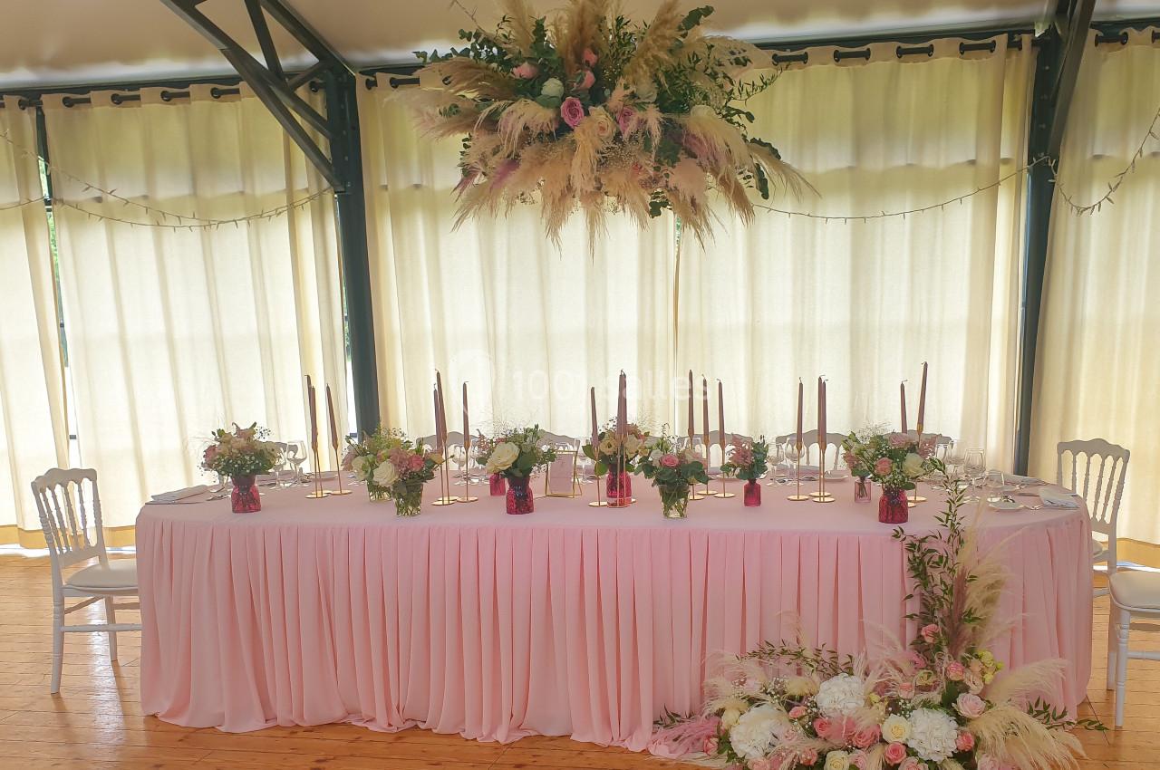Location salle Fontains (Seine-et-Marne) - Château de Bourguignon #31 Table de réception décorée de fleurs, bougies et nappes roses, avec un grand arrangement floral suspendu.