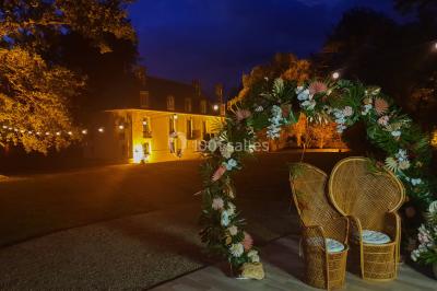 Miniature Location salle Fontains (Seine-et-Marne) - Château de Bourguignon #9 Vue nocturne d'une verrière illuminée par des lumières violettes, entourée d'arbres et d'un jardin.