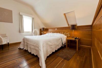 Salle de bain avec baignoire, carrelage blanc et violet, lavabo avec miroir, serviettes pliées et lumière naturelle.