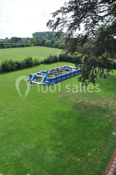 Structure gonflable colorée installée sur une pelouse verte, entourée d'arbres et de haies.