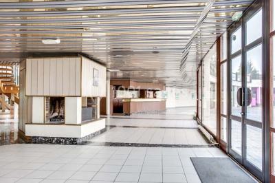 Salle de réception décorée avec des tables rondes, nappes blanches et chaises ornées de nœuds colorés.