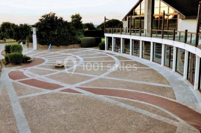 Salle de réception décorée avec des tables rondes, nappes blanches et chaises ornées de nœuds colorés.