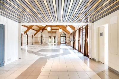 Salle de réception décorée avec des tables rondes, nappes blanches et chaises ornées de nœuds colorés.