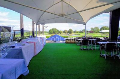 Salle de réception décorée avec des tables rondes, nappes blanches et chaises ornées de nœuds colorés.